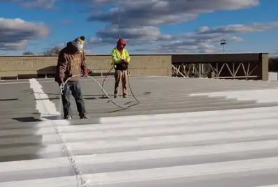 Workers on top of commercial roof applying roof coatings